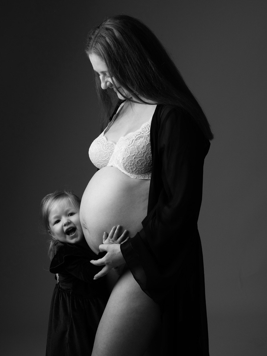 Black and white maternity photograph with a little girl beaming