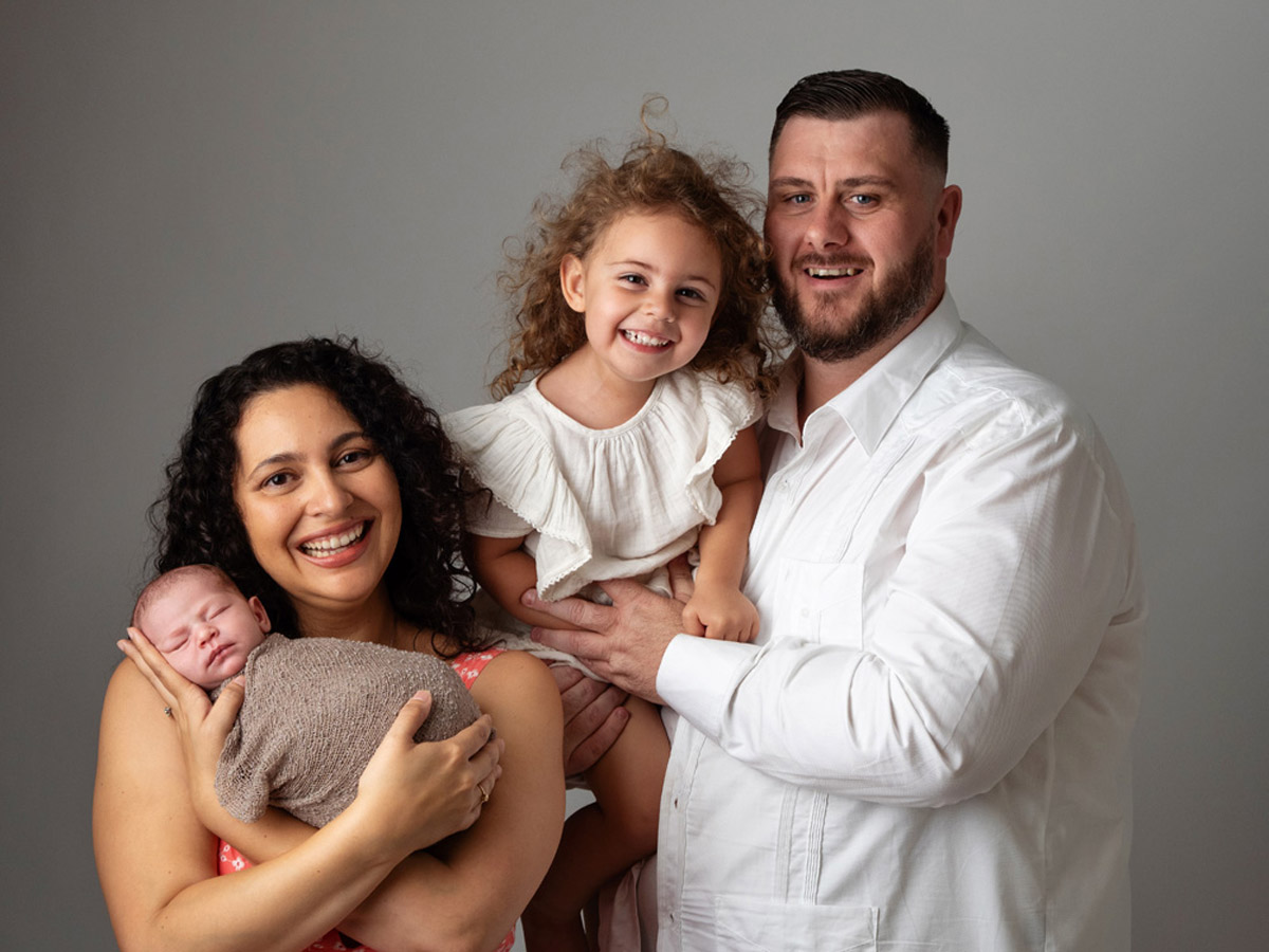 Family holding their newborn baby with a sibling