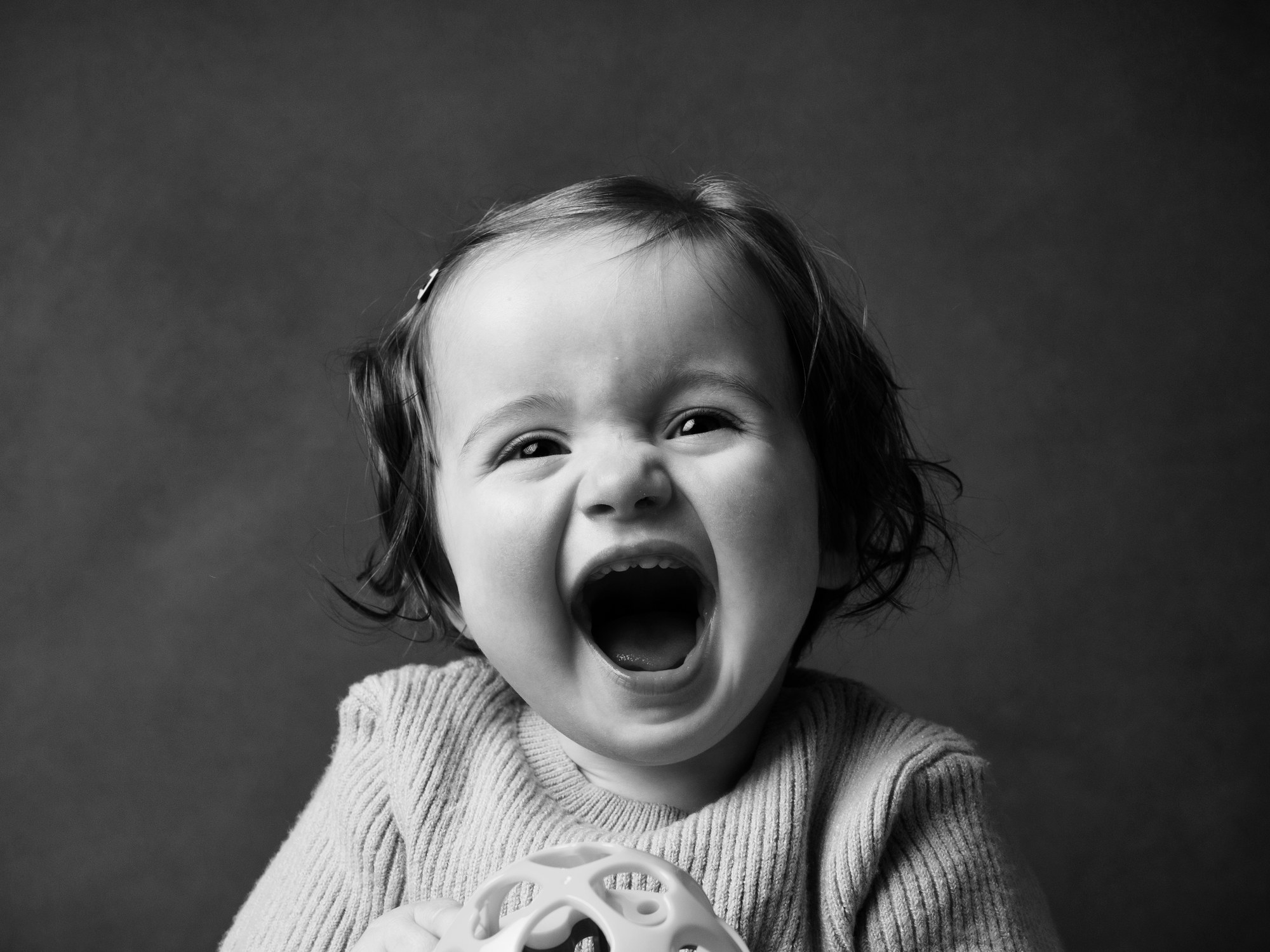 Little one laughing with a toy, black and white