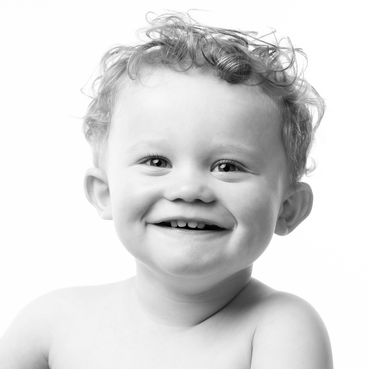 Toddler with curls grinning, black and white