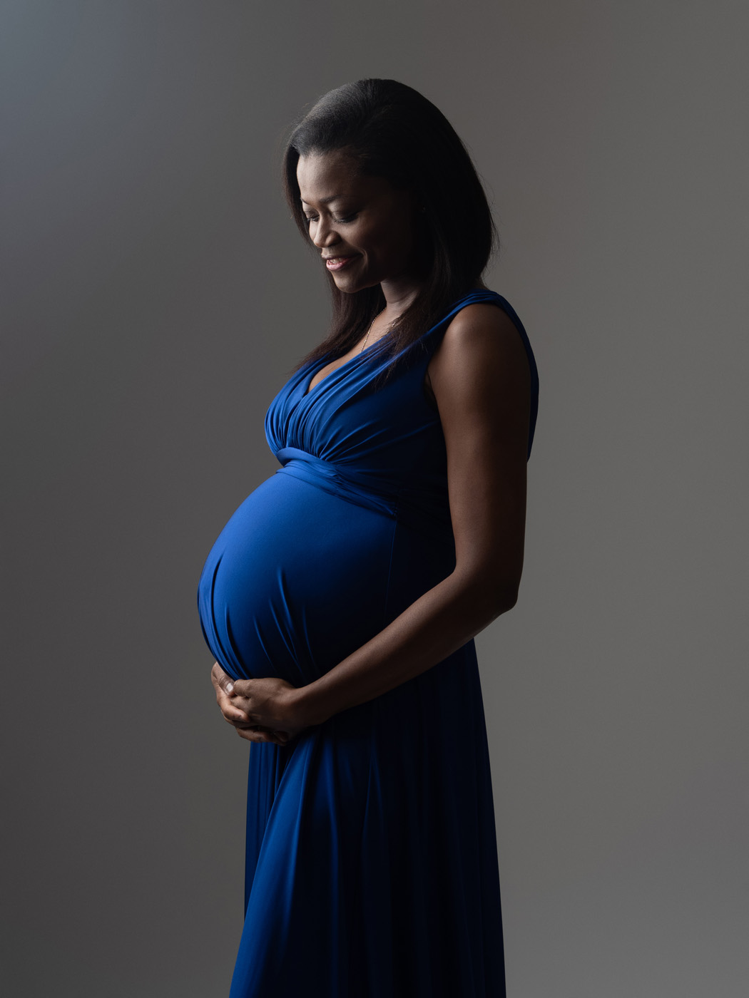 Mum-to-be in a blue gown cradling her bump
