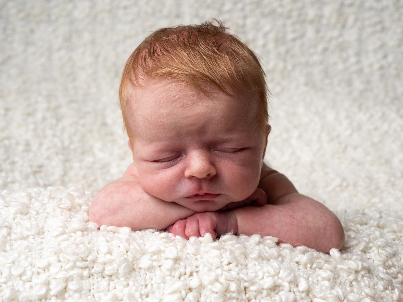 Sleeping newborn resting their chin on their hands