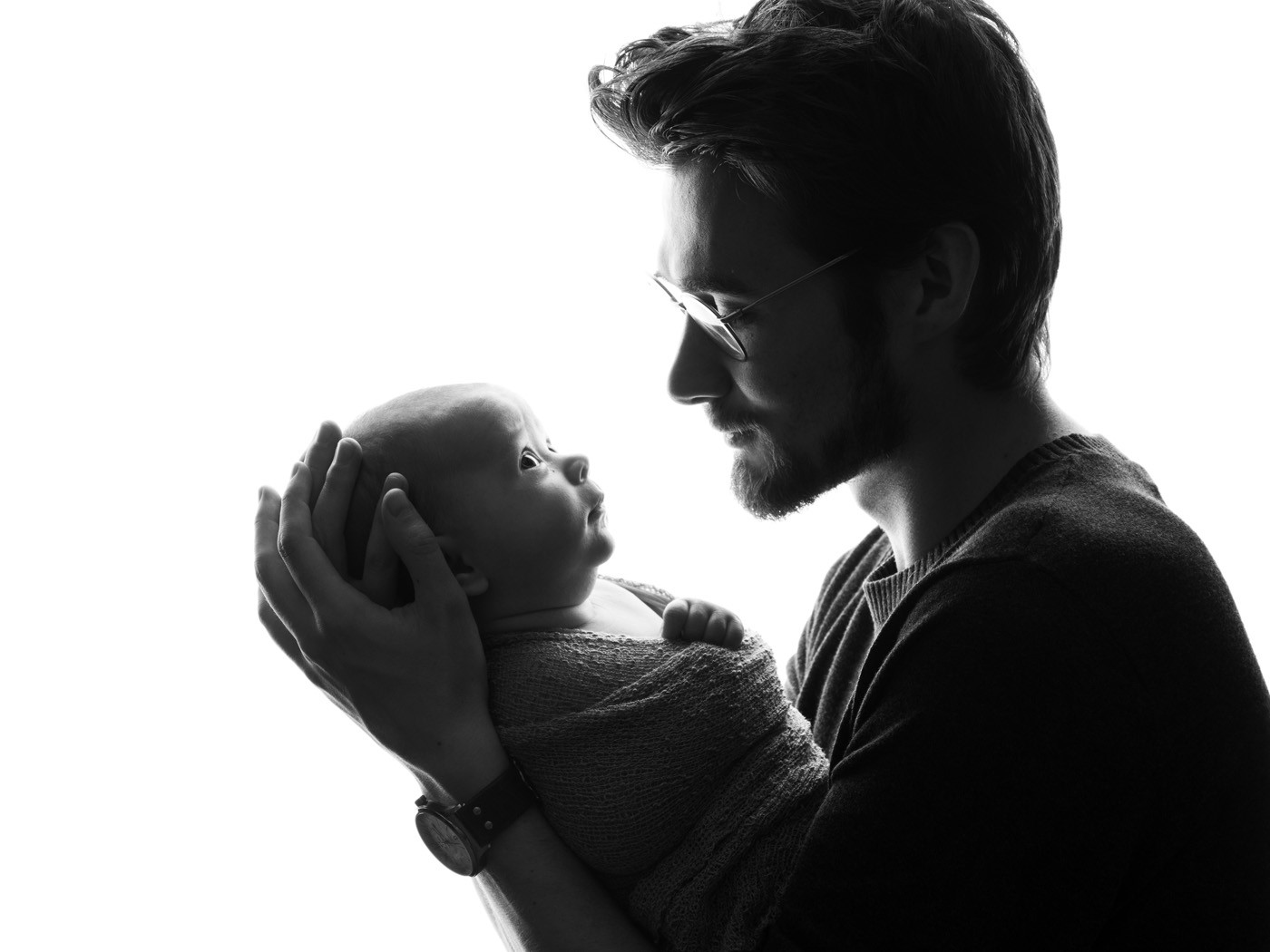 Silhouette of a dad gazing at his newborn baby
