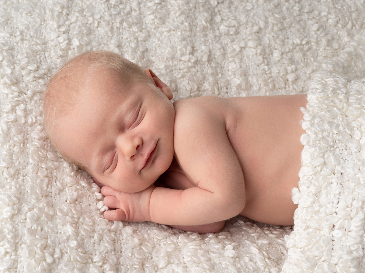 Newborn baby sleeping peacefully on a soft white blanket