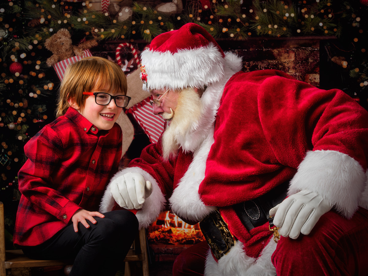 Boy in glasses laughing with Santa