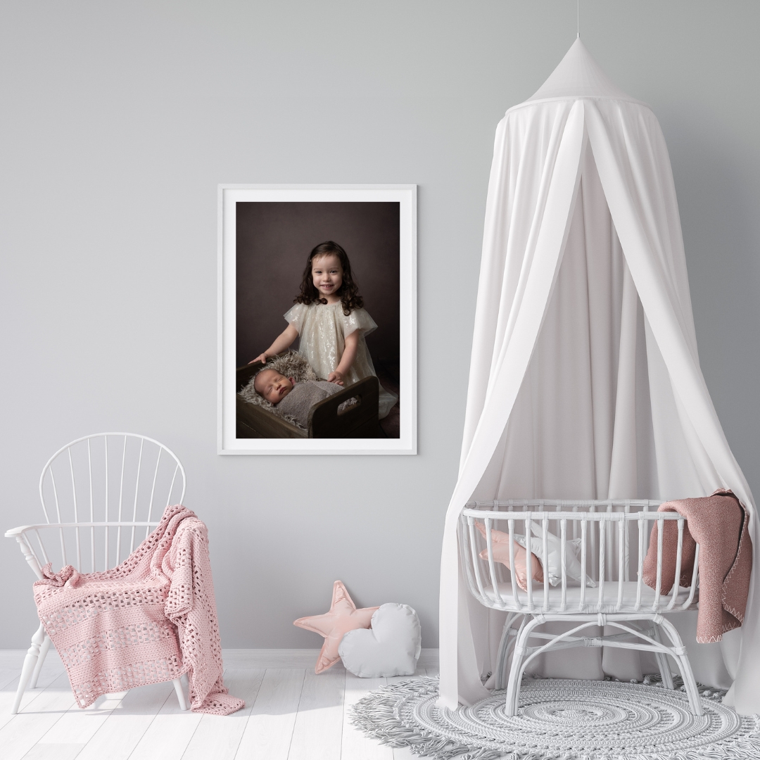 Framed portrait of a big sister with her newborn sibling in a nursery